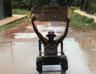 Opositor cubano Silverio Portal protesta sentado en un enorme bache con agua en La Habana